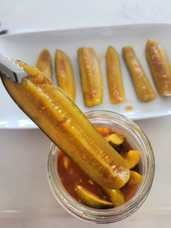 Viral TikTok Taco Pickles on a platter and in a jar with 1 pickle pulling out of the jar. 