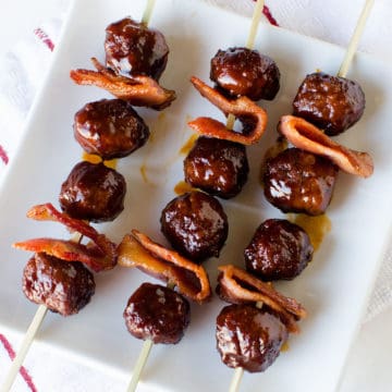 bacon bourbon meatballs on skewers on a white plate
