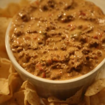 Crock Pot Chili Cheese Dip in a white bowl with chips on a plate