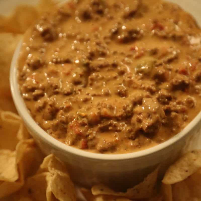 Crock Pot Chili Cheese Dip in a white bowl with chips on a plate