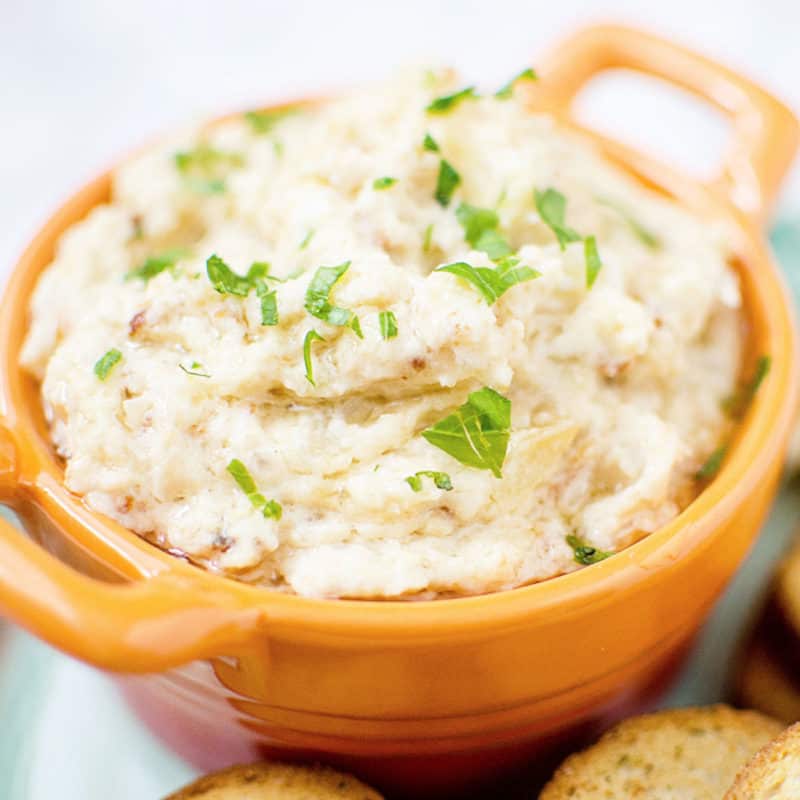 Onion dip in a orange bowl next to crackers