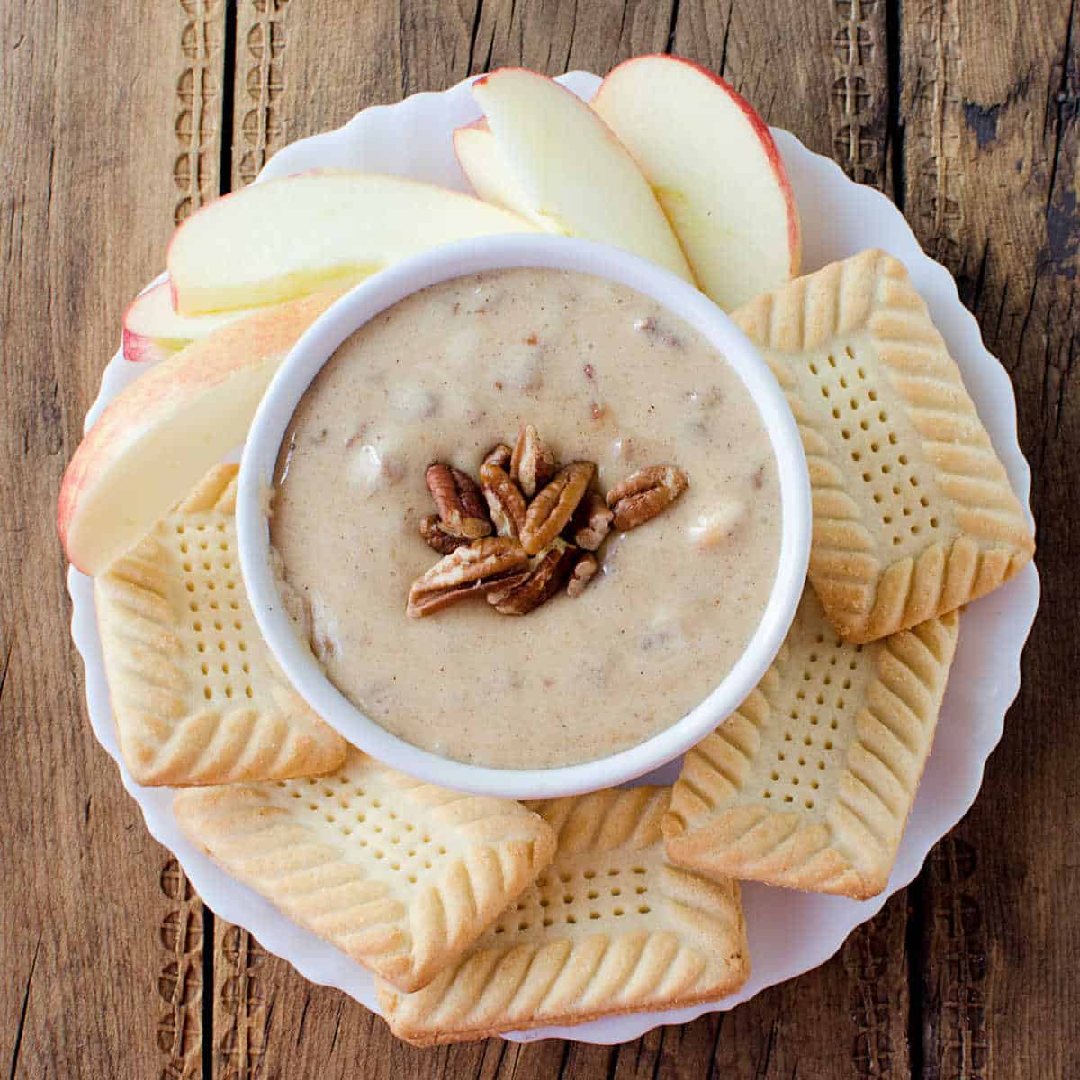 Praline Dip in a white bowl surrounded by cookies and apple slices
