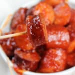 barbecue kielbasa on a toothpick above a bowl full of spicy bbq kielbasa