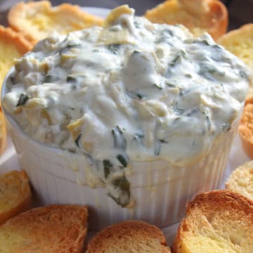 Crock Pot Spinach Artichoke Dip in a white bowl next to toasted bread slices
