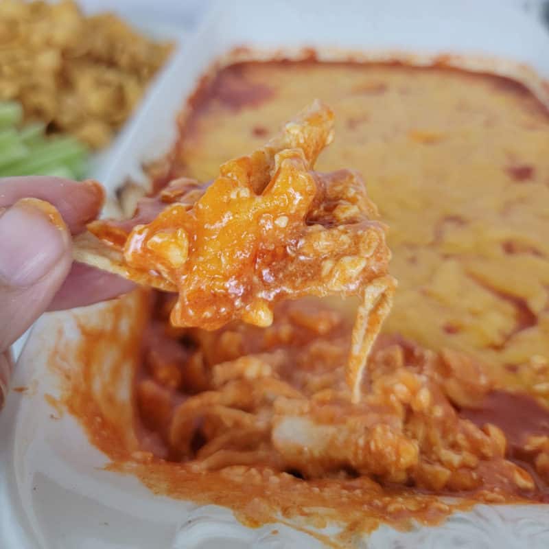 Easy Frank’s Buffalo Chicken Dip on a chip above a full baking dish