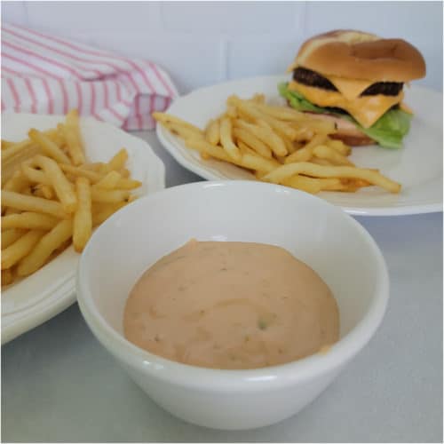 White bowl filled with In n Out Sauce next to a burger and fries