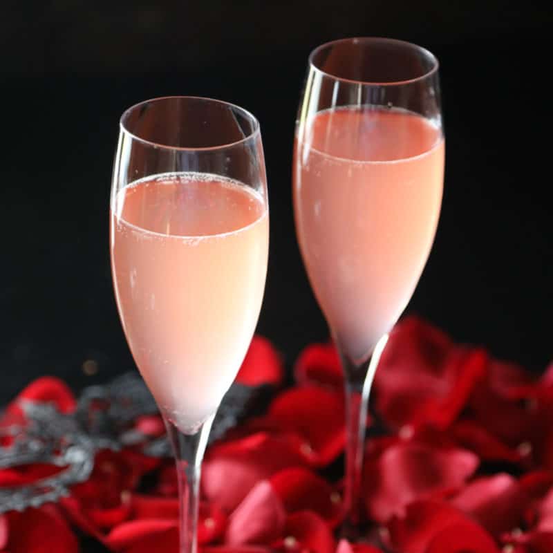 Kinky Bubbles cocktail in champagne glasses with rose pedals spread out
