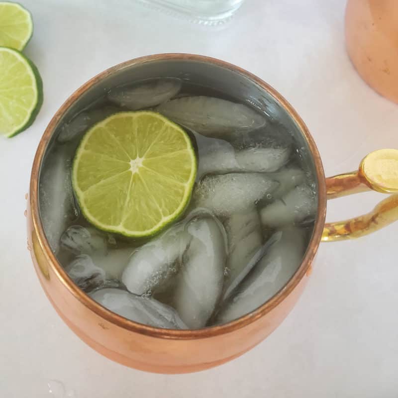 Mexican Mule with a lime circle in a copper mule mug next to more lime circles