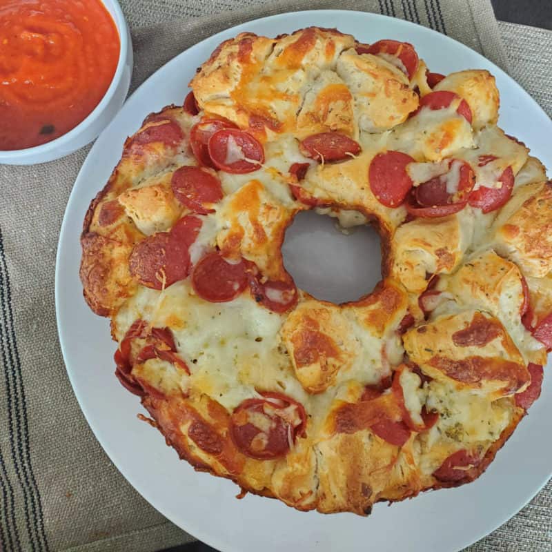 Pepperoni Pizza Monkey Bread on a white plate next to a bowl of marinara