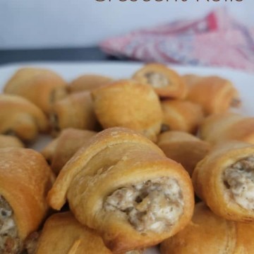 Sausage Cream Cheese Crescent Rolls text over a large plate filled with cream cheese sausage crescent rolls