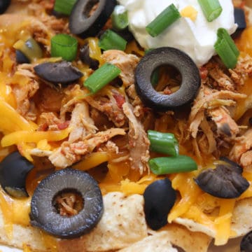 nacho chicken on tortillas with olives, green onions, cheese and sour cream