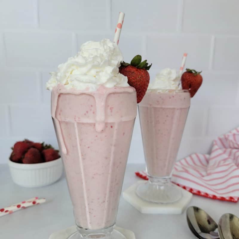 Strawberry Milkshake garnished with whipped cream, a strawberry, and a paper straw