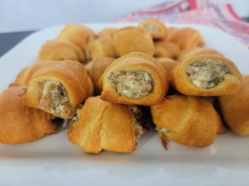 Stack of sausage cream cheese crescent rolls on a white platter