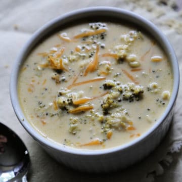 Crock Pot Broccoli Cheese Soup in a white bowl next to a spoon