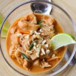 Crock Pot Thai Chicken Stew in a glass bowl next to a spoon and a lime wedge