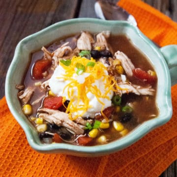 Crockpot Chicken Enchilada Soup in a bowl on a orange cloth napkin next to a spoon