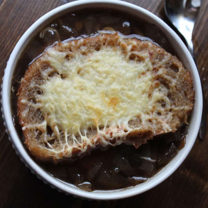 Crockpot French Onion Soup in a white bowl next to a spoon