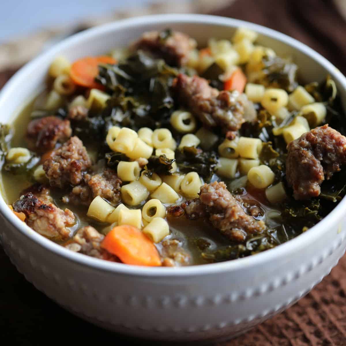 Crockpot Italian Wedding Soup in a white bowl on a brown cloth napkin