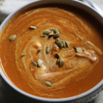 Crockpot Pumpkin Soup garnished with pepita seeds in a white bowl