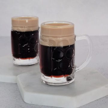 Two baby Guinness shots on white coasters