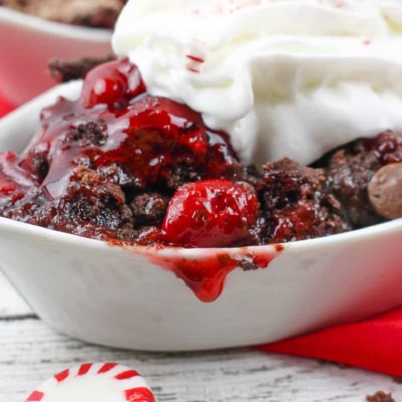Chocolate Peppermint Cherry Dump Cake in a white bowl with whipped cream and peppermint candies