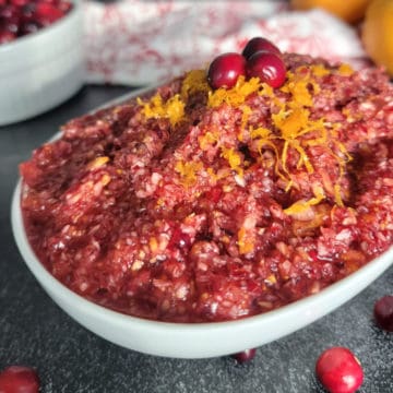 Cranberry Orange Relish in a white bowl garnished with citrus zest and cranberries