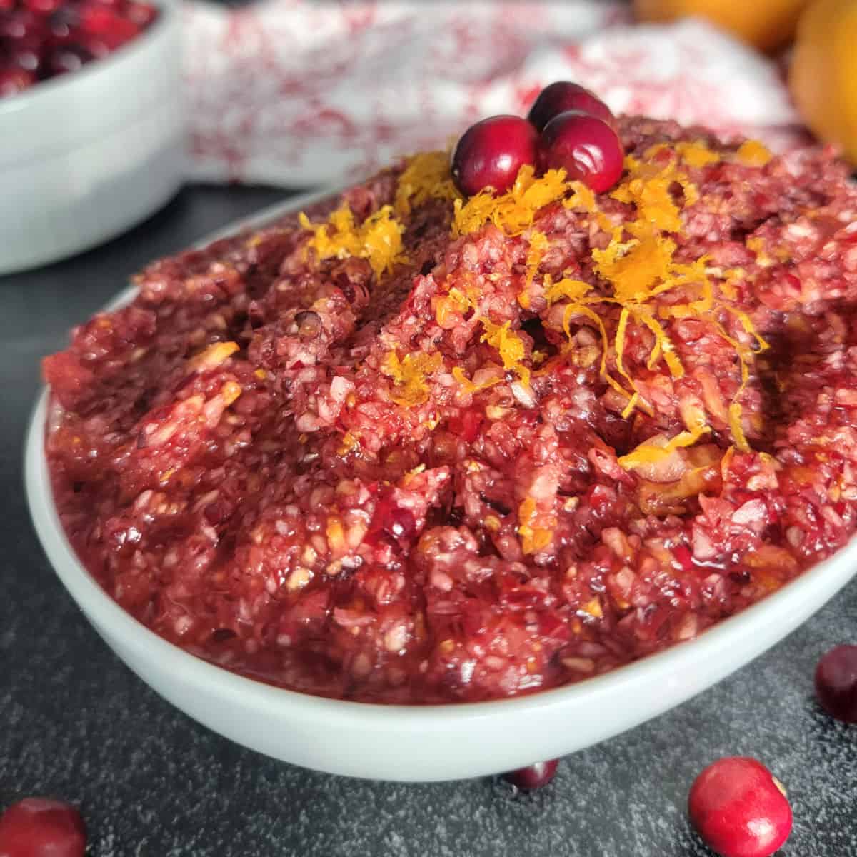 Cranberry Orange Relish in a white bowl garnished with citrus zest and cranberries