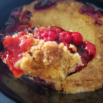 Cherry Dump Cake on a spoon above the slow cooker