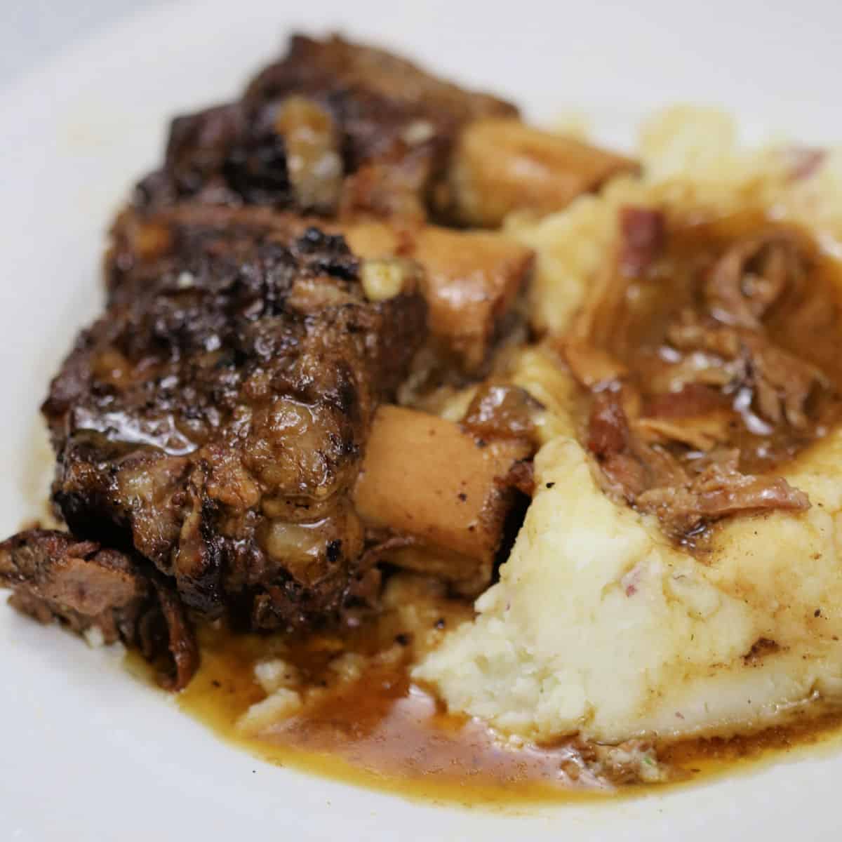 Guinness braised short ribs next to mashed potatoes on a white plate