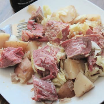 Crockpot Guinness corned beef and cabbage with potatoes on a white plate