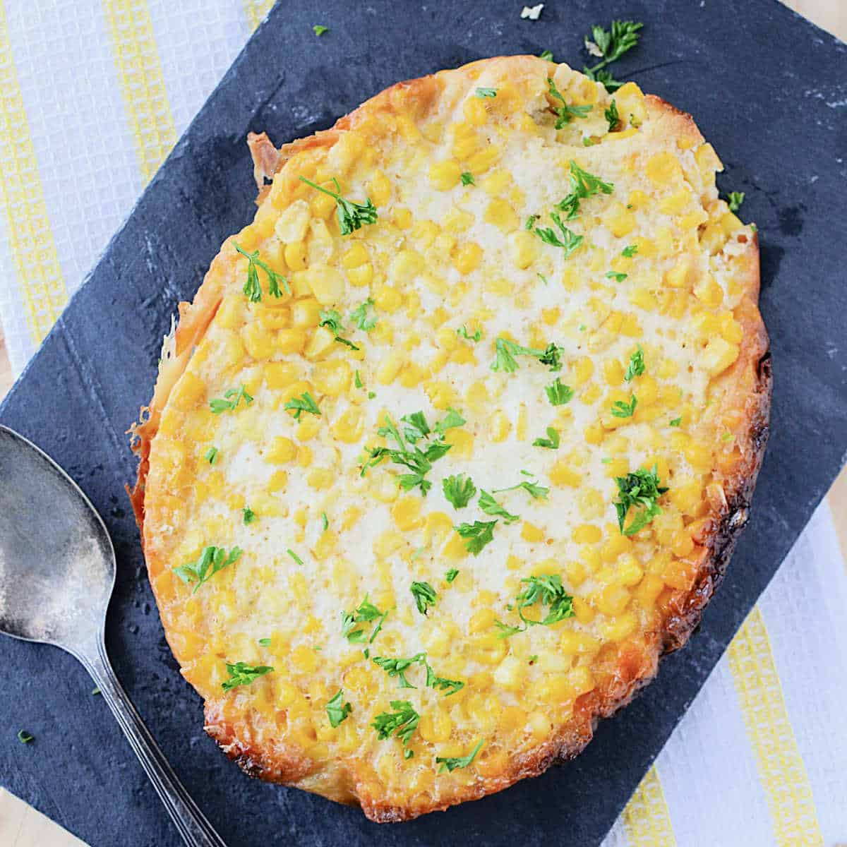 corn pudding on a slate board with a spoon