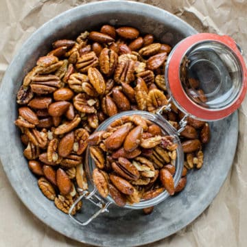 sweet and spicy nuts spread on a silver tray with a glass jar
