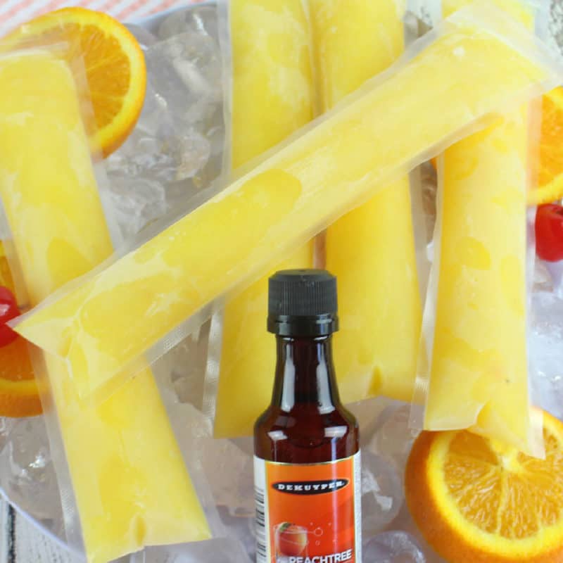 Fuzzy Navel boozy popsicles on a bed of ice with oranges