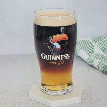 Guinness and Cider layered cocktail on a white coaster