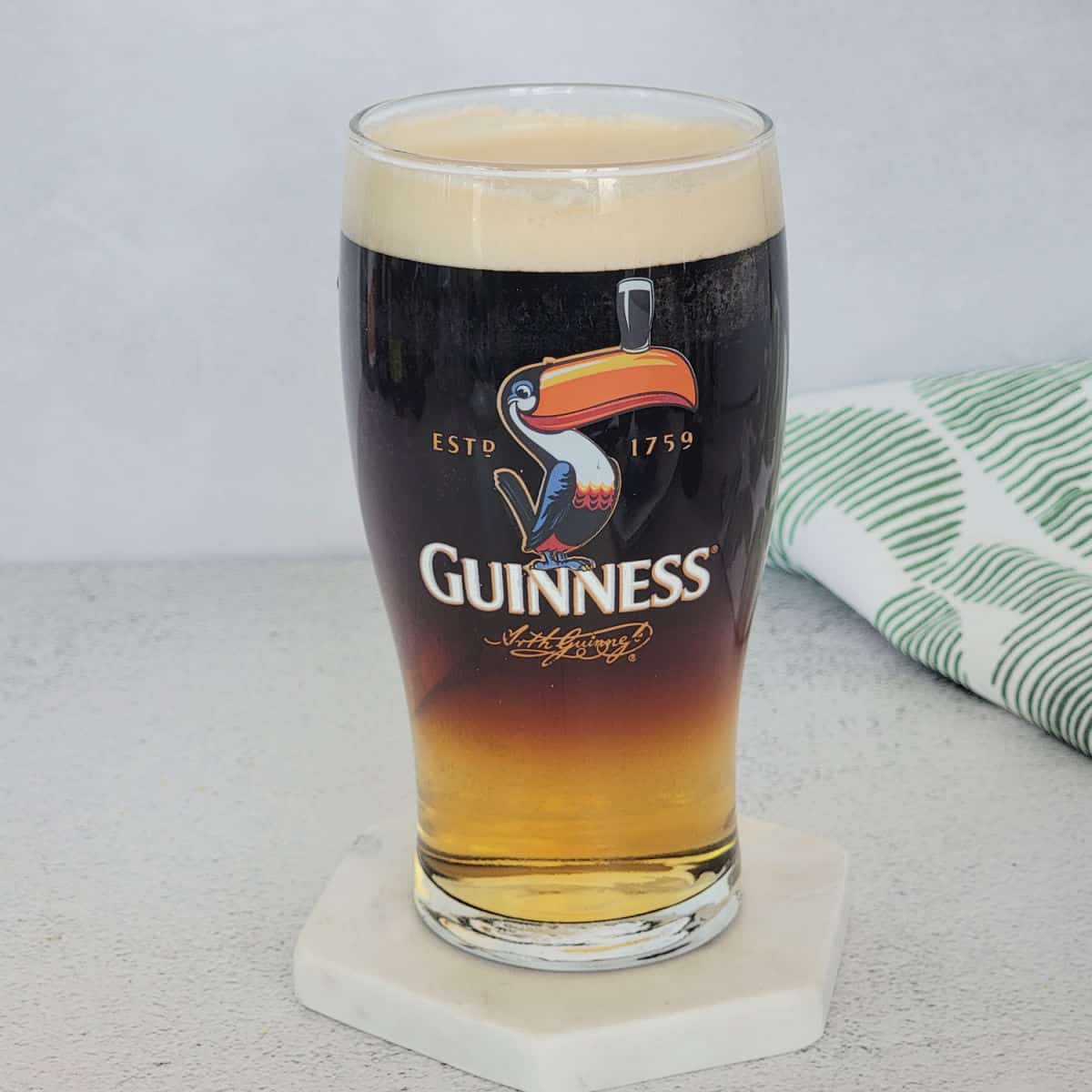 Guinness and Cider layered cocktail on a white coaster