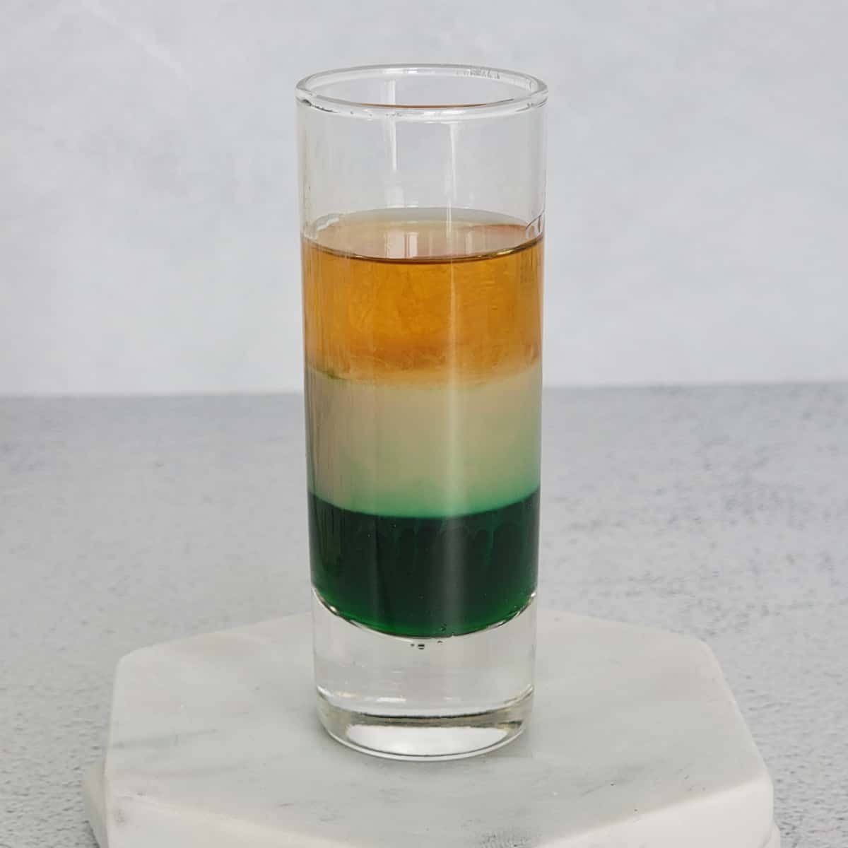 Irish Flag layered shot in a glass shot glass on a marble coaster