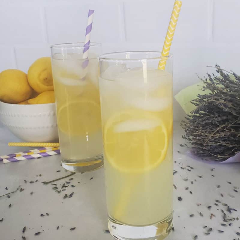 Lavender Lemonade Cocktail in tall glasses with paper straws next to a bowl of lemons