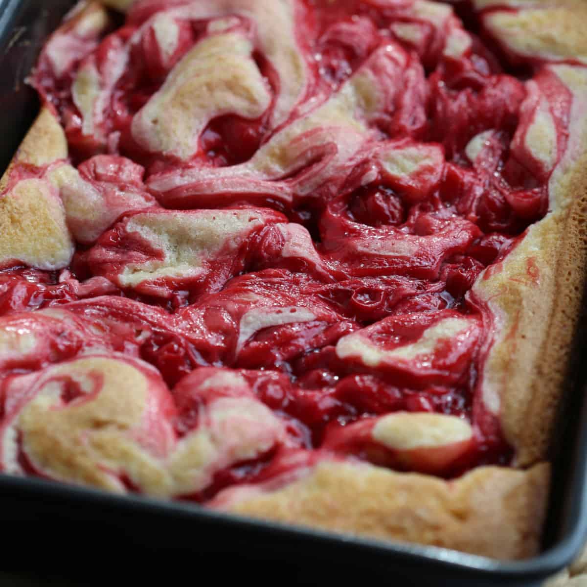 Cherry Pie Cake in baking dish with cherry swirls on top