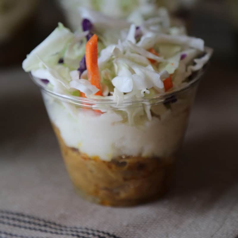 Pulled pork parfait in a plastic cup on a cloth napkin
