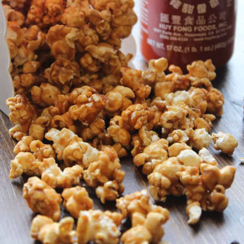 Sriracha caramel popcorn spread out from a popcorn container 