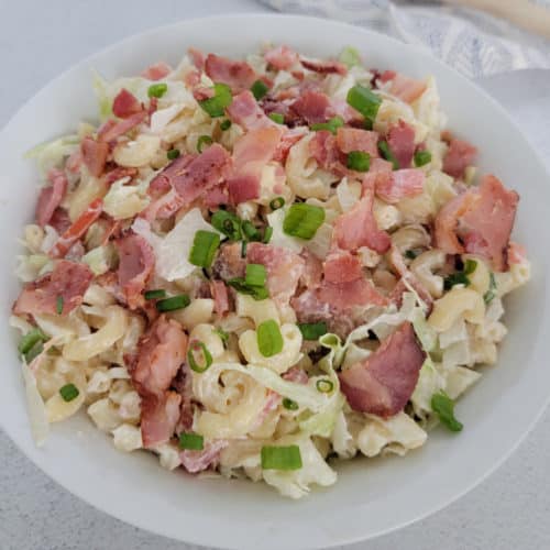 BLT pasta salad garnished with green onion in a white bowl