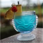 Blue Hawaiian Cocktail in a tiki glass with pineapple wedge and cherry garnish