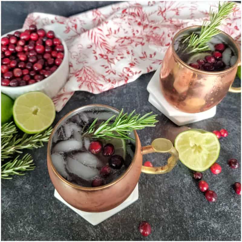 cranberry mules in copper mugs with a bowl of cranberries and lime slices