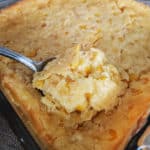 Creamed Corn Casserole on a silver spoon lifting out of a casserole dish
