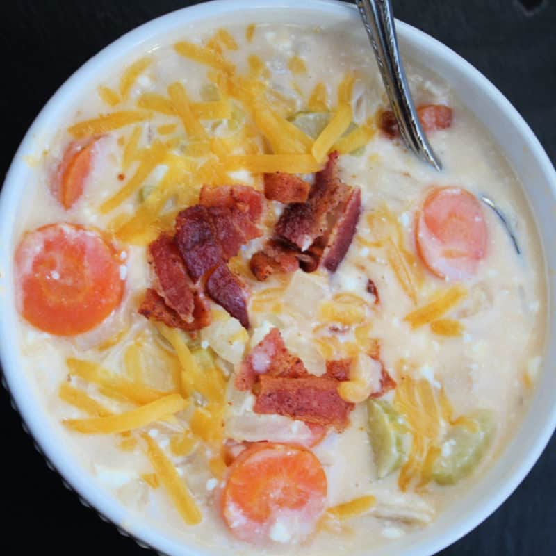 beer cheese soup with bacon garnish in a white bowl with silver spoon