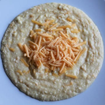 cheese grits topped with shredded cheese in a white bowl