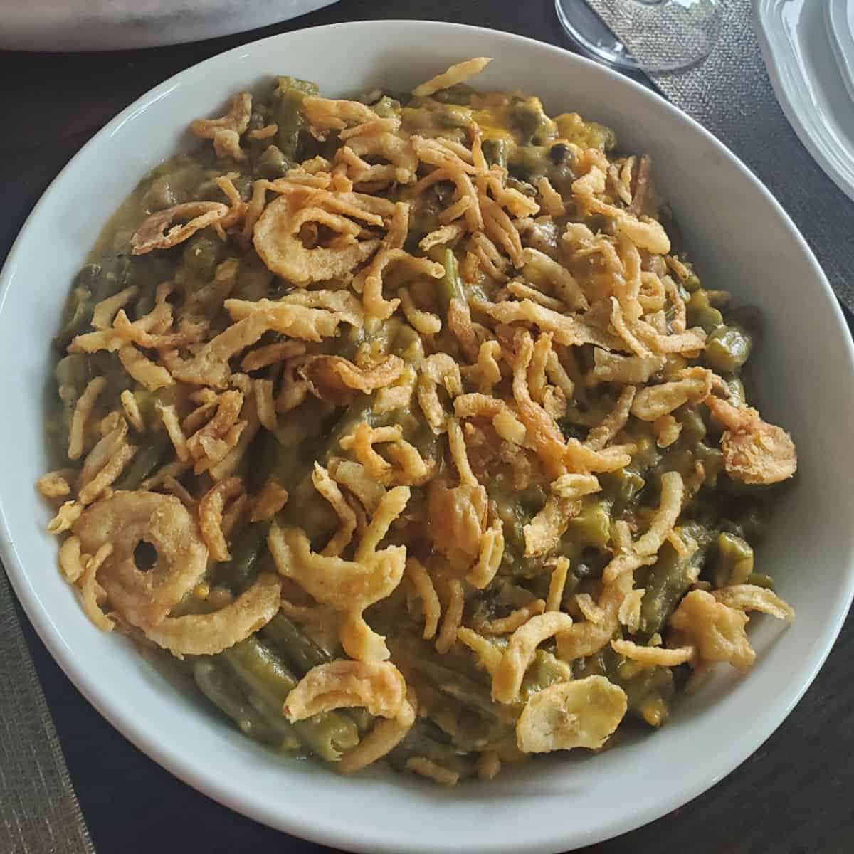 fried onions on top of green beans in a white bowl