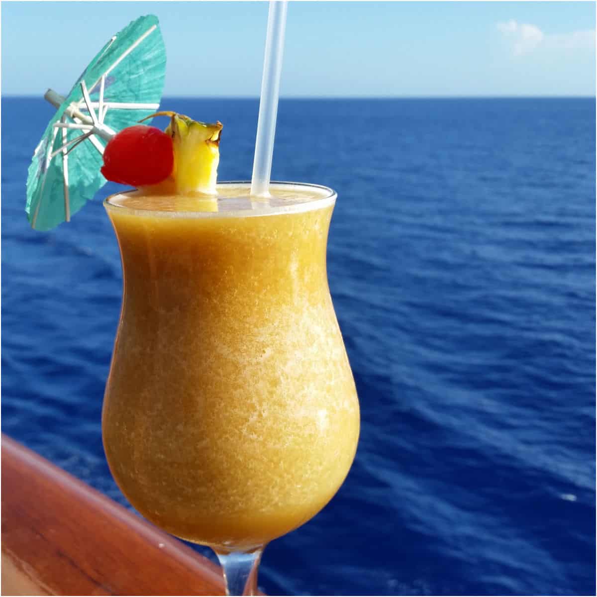 Yellow dirty banana cocktail in a hurricane glass with the ocean background