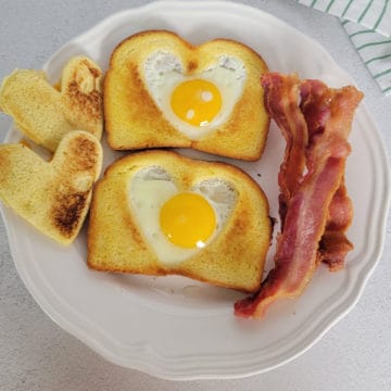 Eggs in the middle of toast next to bacon