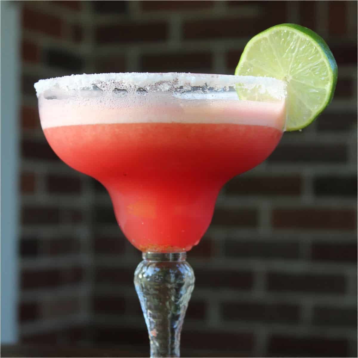 watermelon margarita in a margarita glass with a lime wheel